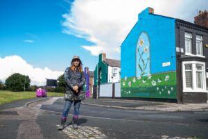 Madeleine Pires, artist of Flower Streets, in front of large floral mural.
