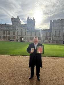 Mark King OBE, receiving his award outside Bucking Palace