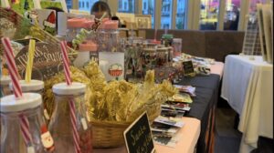 An image of one of the market stall tables, featuring festive water bottles with candy cane coloured straws, goody bags, shots glasses, prosecco flutes and mugs on sale.