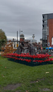 Statue of soldiers outside Bombed Out Church surrounded by poppies