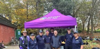 A photo of Chris Boardman CBE with the team of staff and volunteers at Wheels for All Birkenhead Park.