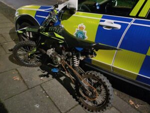Scrambler bike leaning up against a police car