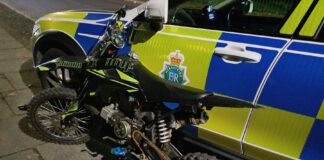 Scrambler bike leaning up against a police car