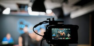 A close-up of a camera filming a set, out of focus