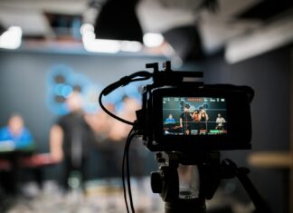 A close-up of a camera filming a set, out of focus