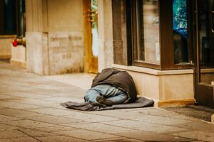 Homeless person sleeping rough outside a shop