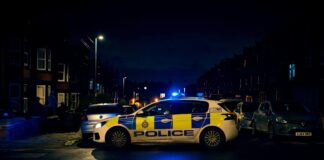 Police car parked on the side of the road at night with sirens on