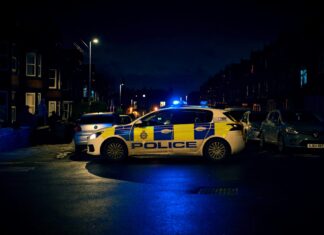 Police car parked on the side of the road at night with sirens on