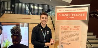 A picture of JMSU President Miles Craven holding a 'Change Please' coffee cup.