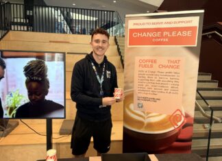 A picture of JMSU President Miles Craven holding a 'Change Please' coffee cup.