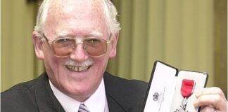 An image of Bill Tidy smiling as he receives his MBE