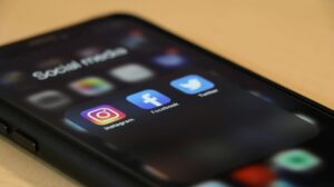 Black Iphone showing several social media apps, including instagram, facebook and X