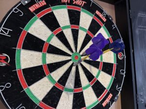 Image shows dart board with darts thrown onto it