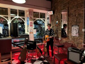 Musician Sam Taylor performing with a guitar at Rockpoint Records