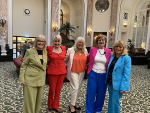 the five women standing together smiling