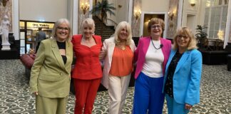 the five women standing together smiling