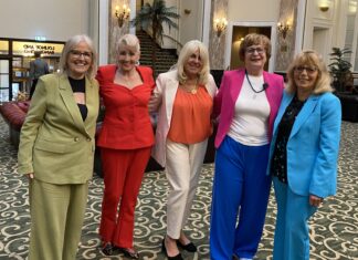 the five women standing together smiling