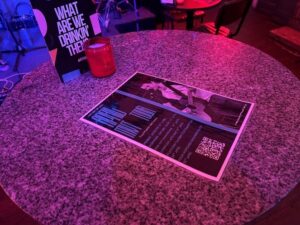 Tour posters with barcodes on on the tables in Arts Bar